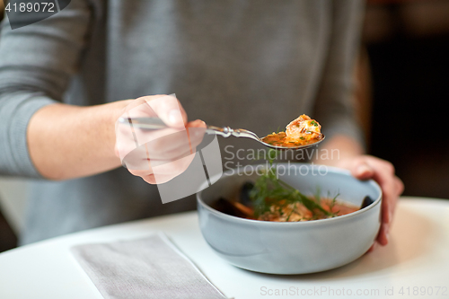 Image of woman eating fish soup at cafe or restaurant