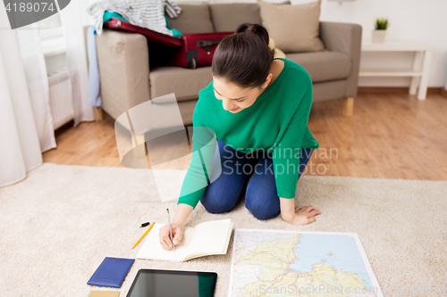 Image of woman with notebook and travel map at home