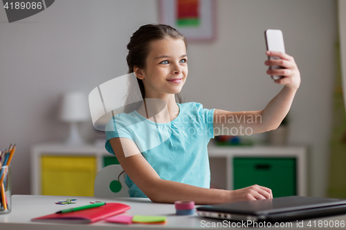 Image of happy girl with smartphone taking selfie at home