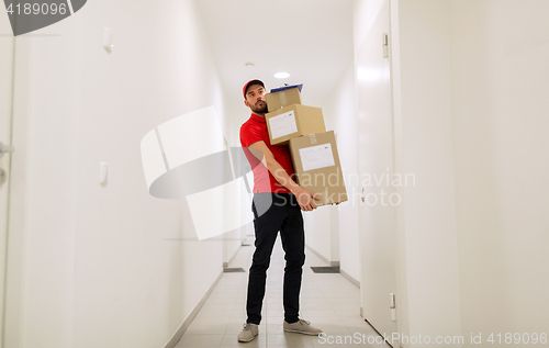 Image of delivery man with parcel boxes in corridor