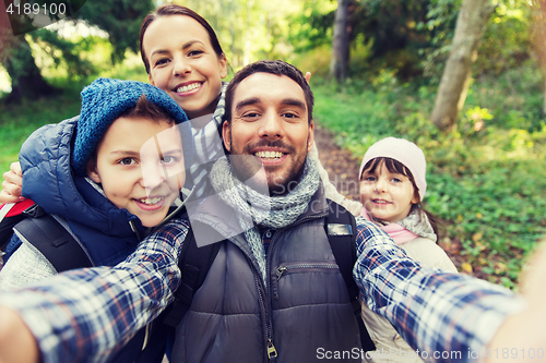 Image of family with backpacks taking selfie and hiking