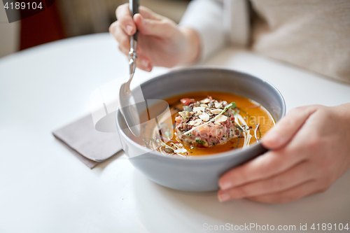 Image of woman eating pumpkin cream soup at restaurant