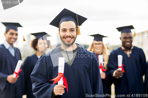 Image of happy students in mortar boards with diplomas