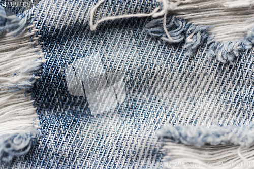 Image of close up of holes on shabby denim or jeans clothes