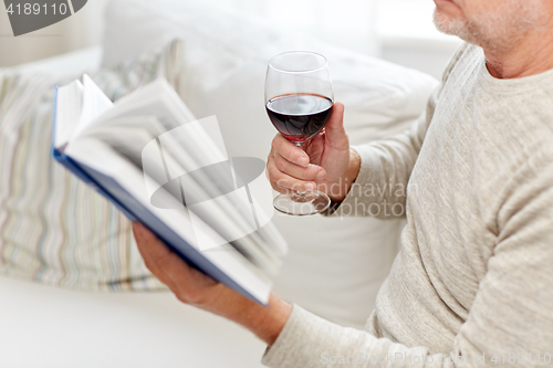 Image of close up of senior man with wine reading book