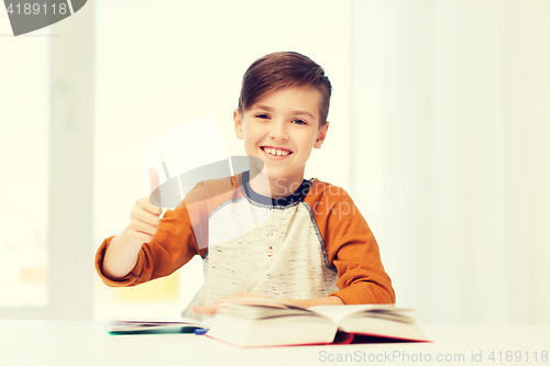 Image of happy student boy with textbook showing thumbs up
