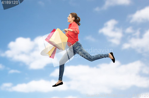 Image of smiling young woman with shopping bags jumping