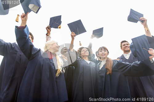 Image of happy students or bachelors waving mortar boards
