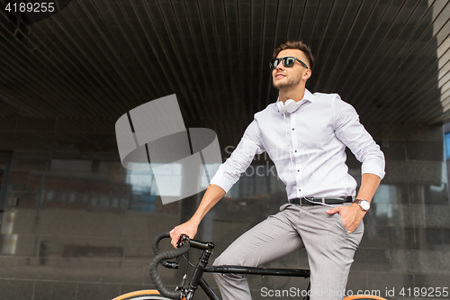 Image of man with bicycle and headphones on city street