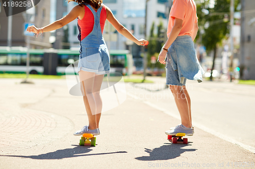 Image of teenage couple riding skateboards on city street