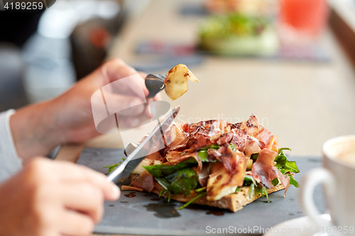 Image of woman eating prosciutto ham salad at restaurant