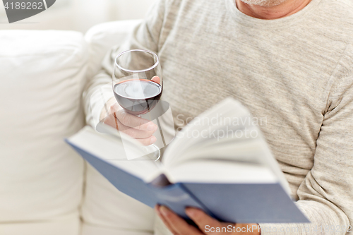 Image of close up of senior man with wine reading book