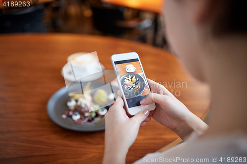 Image of woman with smartphone photographing food at cafe