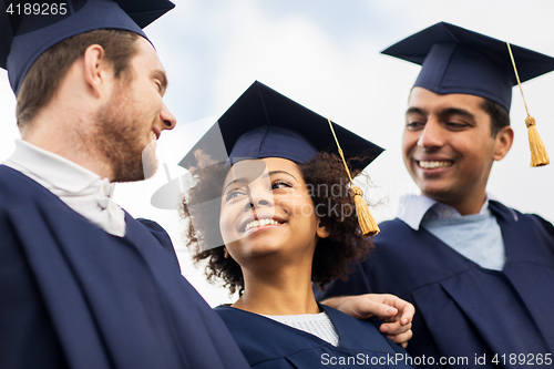 Image of happy students or bachelors in mortar boards