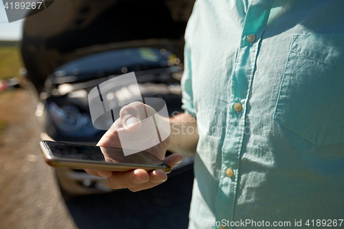 Image of close up of man with smartphone and broken car