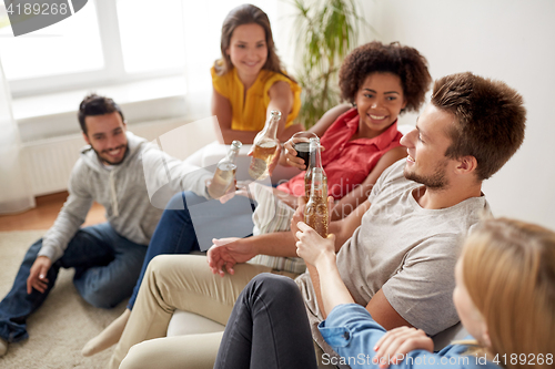 Image of group of happy friends with drinks talking at home