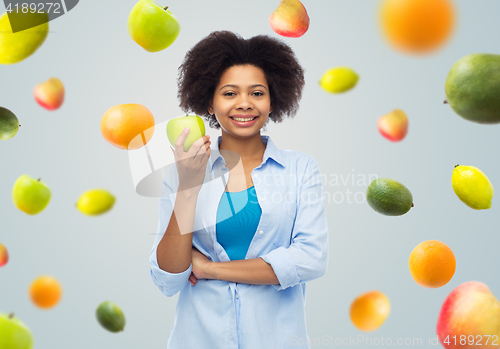 Image of happy african american woman with green apple