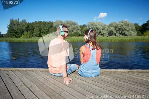 Image of teenage couple with headphones on river berth