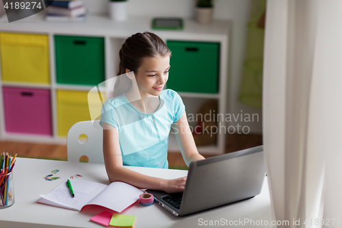 Image of happy girl typing on laptop at home