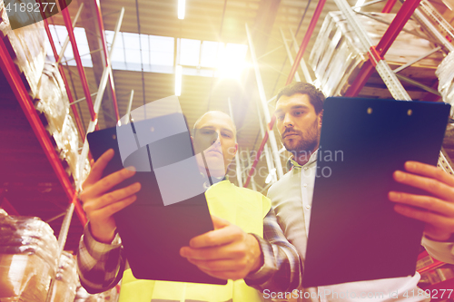 Image of worker and businessmen with clipboard at warehouse