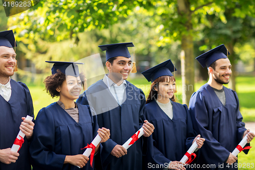 Image of happy students in mortar boards with diplomas