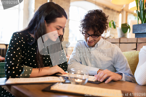 Image of happy friends looking to menu at restaurant