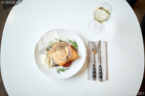 Image of fish salad and wine glass on restaurant table
