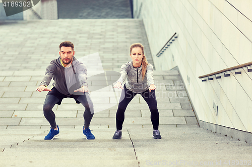 Image of couple doing squats and exercising outdoors