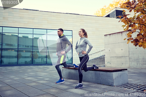 Image of happy man and woman exercising on bench outdoors