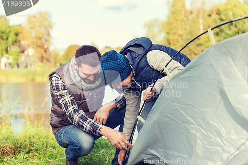 Image of happy father and son setting up tent outdoors