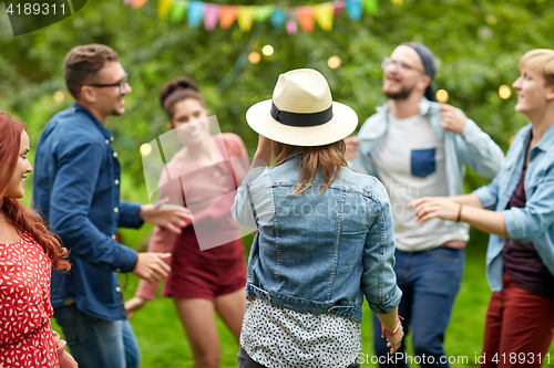 Image of happy friends dancing at summer party in garden