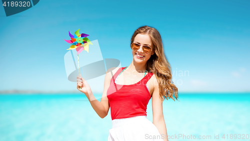 Image of happy woman with pinwheel over blue sky and sea