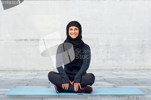 Image of muslim woman doing sport on mat