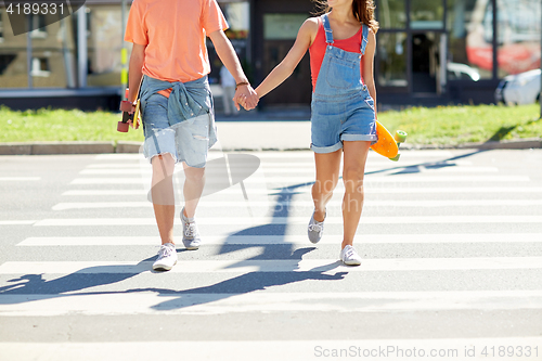 Image of teenage couple with skateboards on city crosswalk