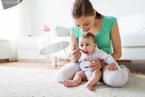 Image of mother with spoon feeding little baby at home