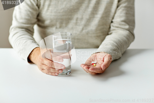 Image of close up of hands with medicine pills and water