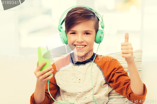 Image of happy boy with smartphone and headphones at home