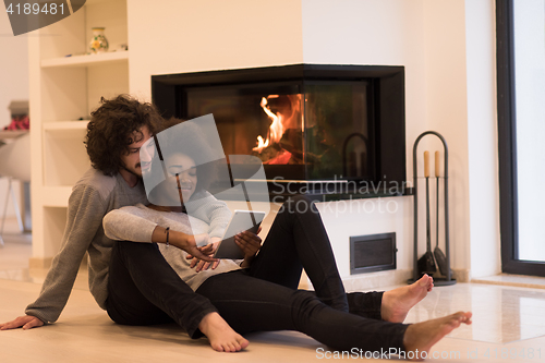 Image of multiethnic couple used tablet computer on the floor