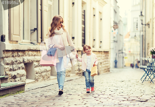 Image of happy mother and child with shopping bags in city