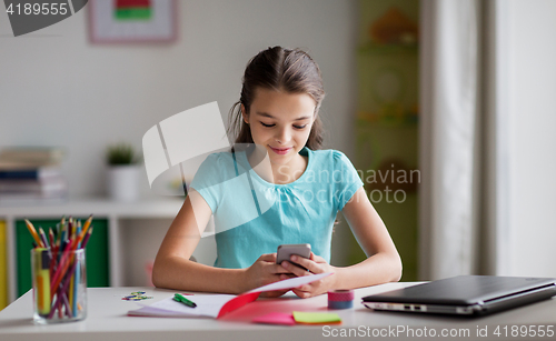 Image of girl with smartphone distracting from homework
