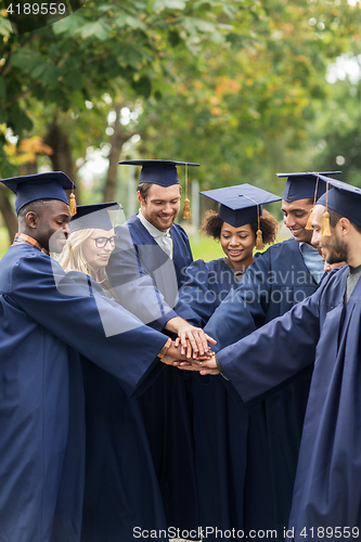 Image of happy students in mortar boards with hands on top