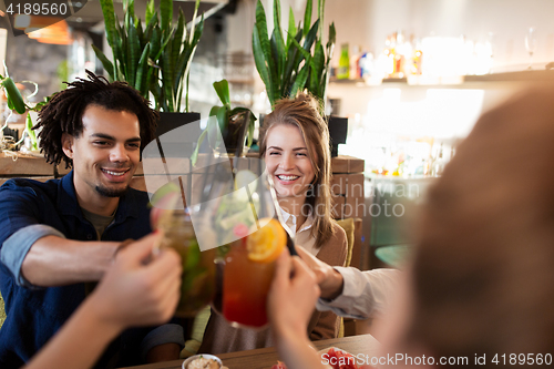 Image of happy friends clinking drinks at restaurant