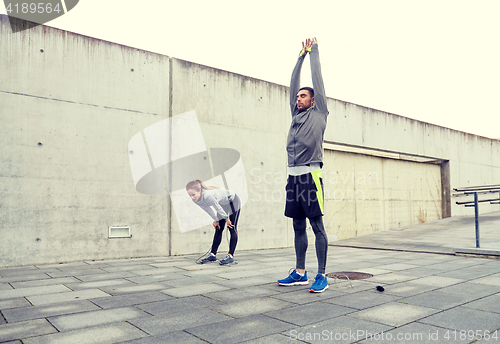 Image of tired couple stretching after exercise