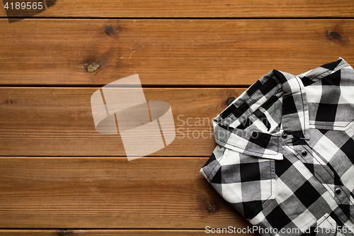 Image of close up of checkered shirt on wooden background