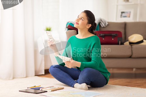 Image of happy woman with money and travel map at home