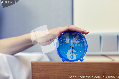 Image of close up of hand on alarm clock in bedroom