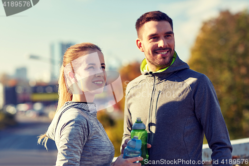 Image of smiling couple with bottles of water outdoors