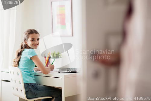 Image of girl with laptop writing to notebook at home