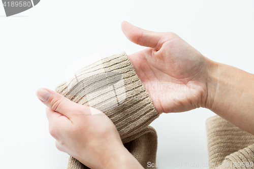 Image of close up of hands with sweater sleeve