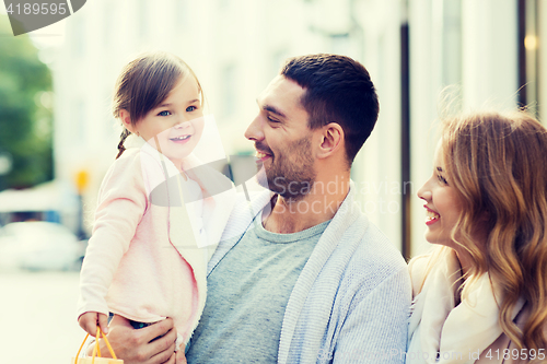 Image of happy family with child and shopping bags in city